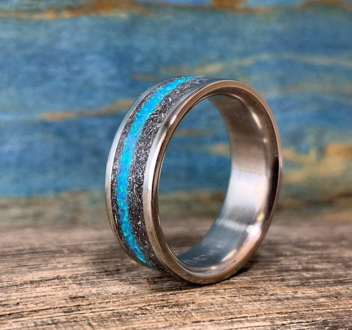 A side view of the upright ring on a wooden surface reveals its polished inner band and textured outer inlay.