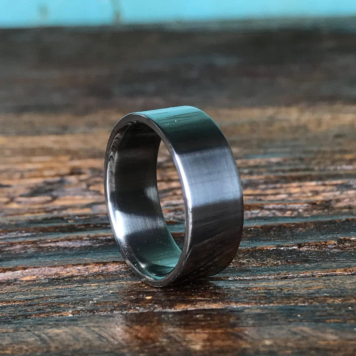 A simple dark metal ring positioned vertically on a wooden tabletop.