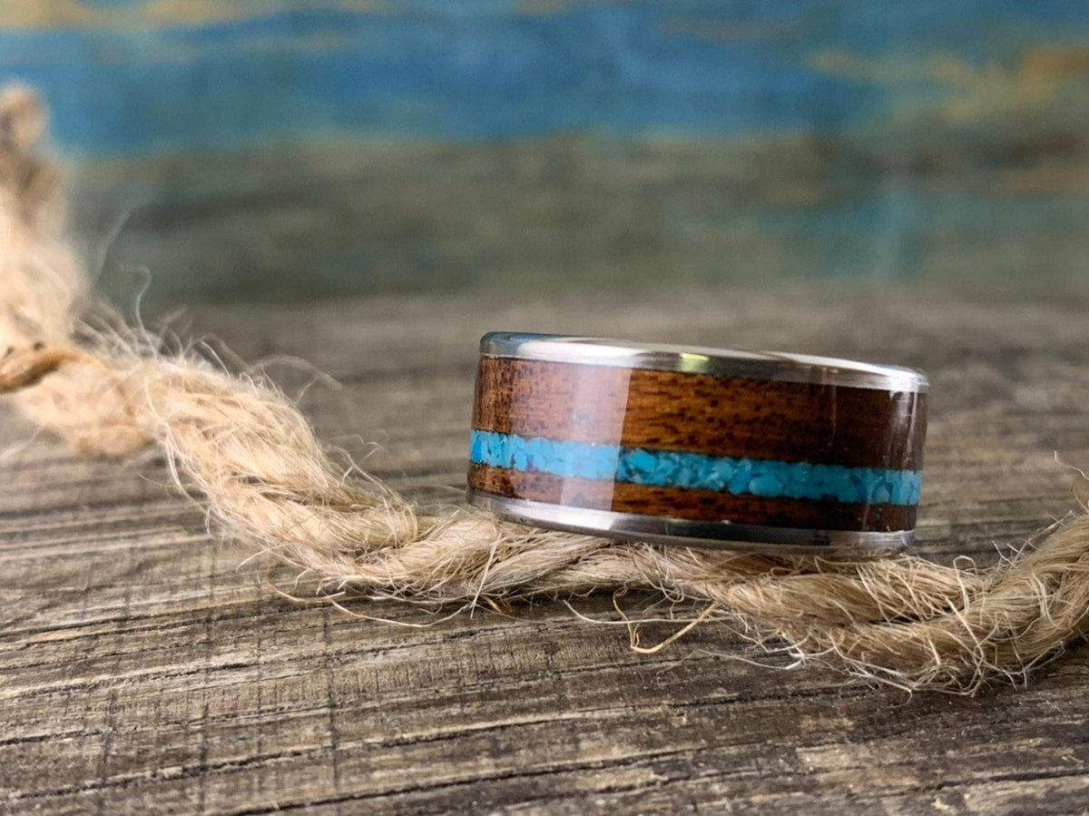 The ring lies horizontally on a weathered wooden surface next to a piece of natural twine.