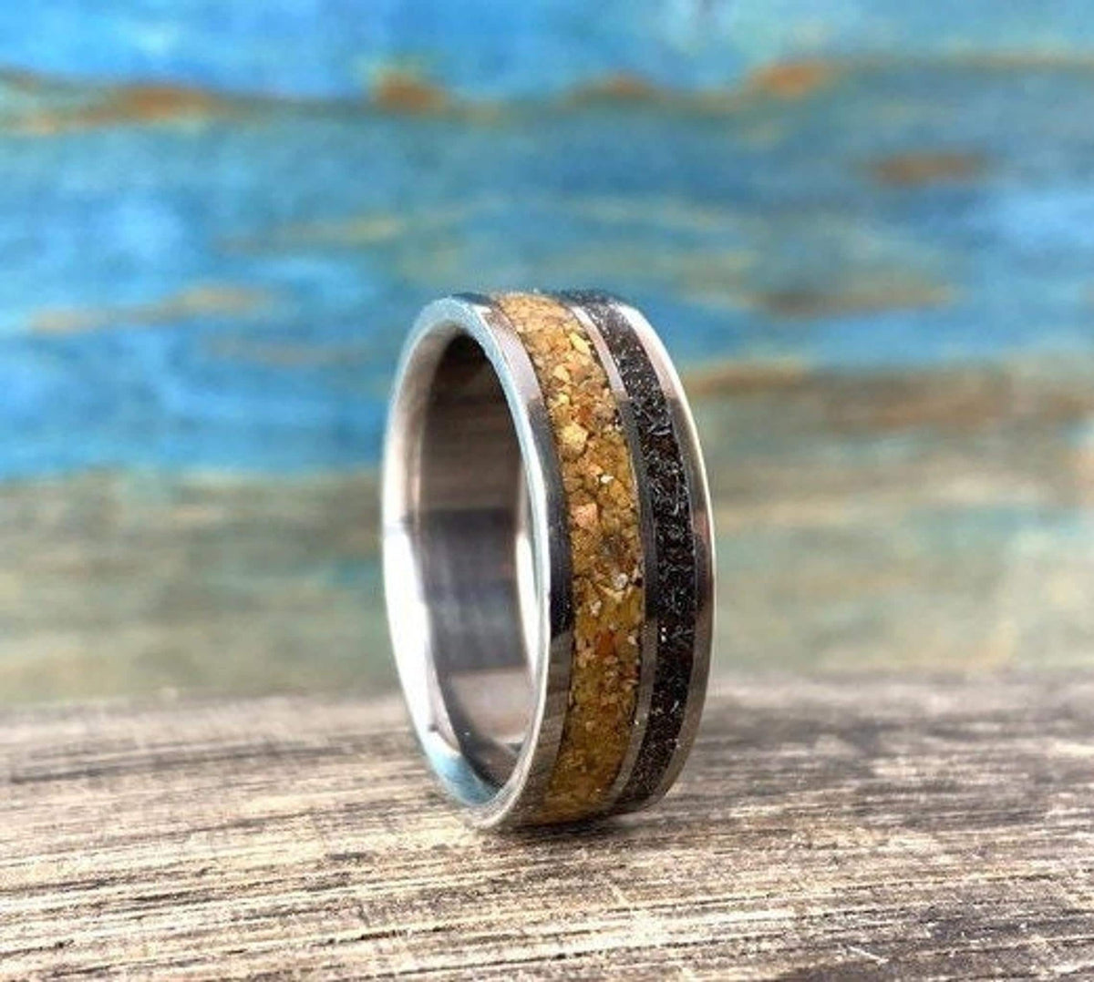 A side view of a metal ring showcasing its internal smooth finish and external wood and meteorite inlays.