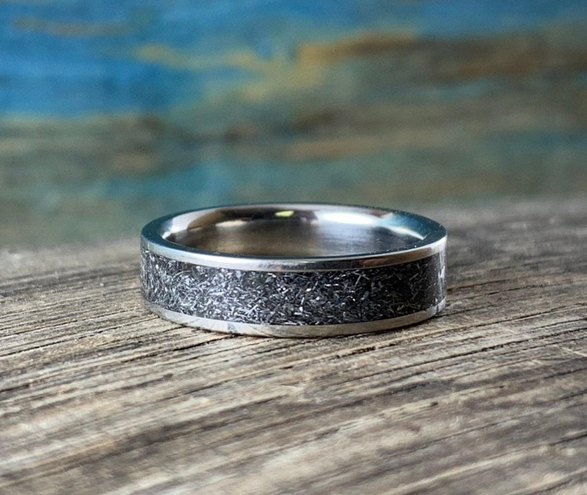 A close-up shot of the ring resting flat, focusing sharply on the metallic sparkle of the patterned inlay.