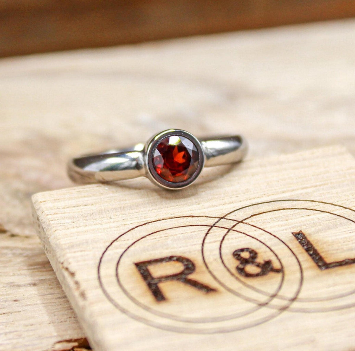Handmade garnet bezel set titanium ring. 5mm round faceted garnet ring. Custom made titanium wedding band.