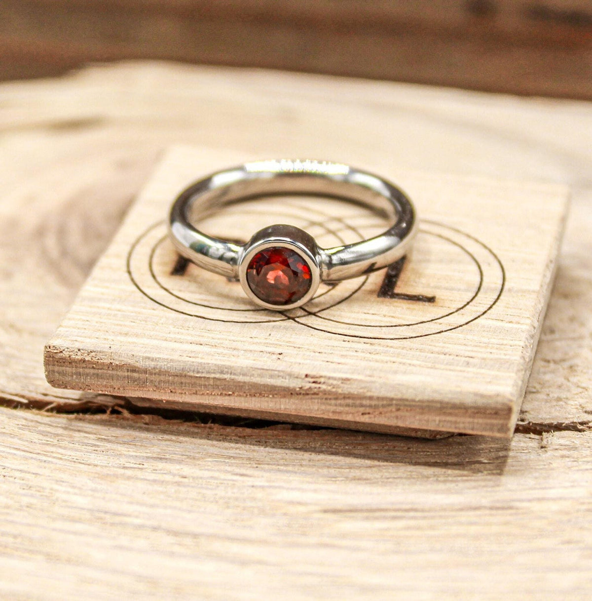 Handmade garnet bezel set titanium ring. 5mm round faceted garnet ring. Custom made titanium wedding band.