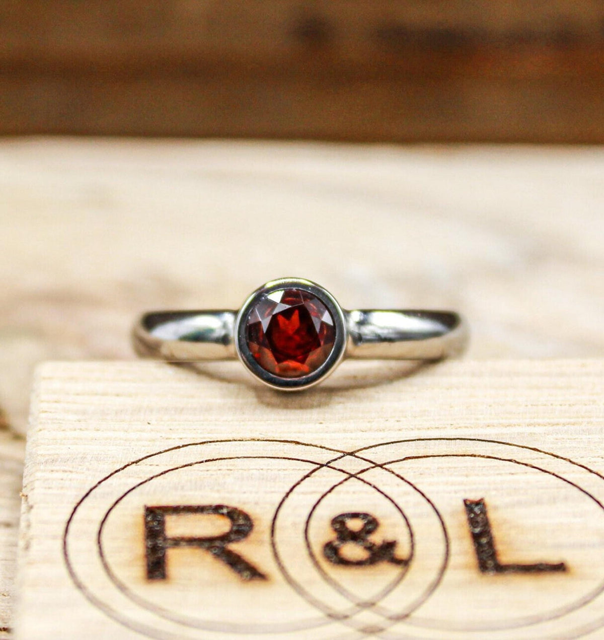 Handmade garnet bezel set titanium ring. 5mm round faceted garnet ring. Custom made titanium wedding band.
