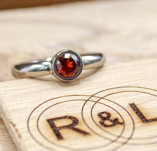 Handmade garnet bezel set titanium ring. 5mm round faceted garnet ring. Custom made titanium wedding band.