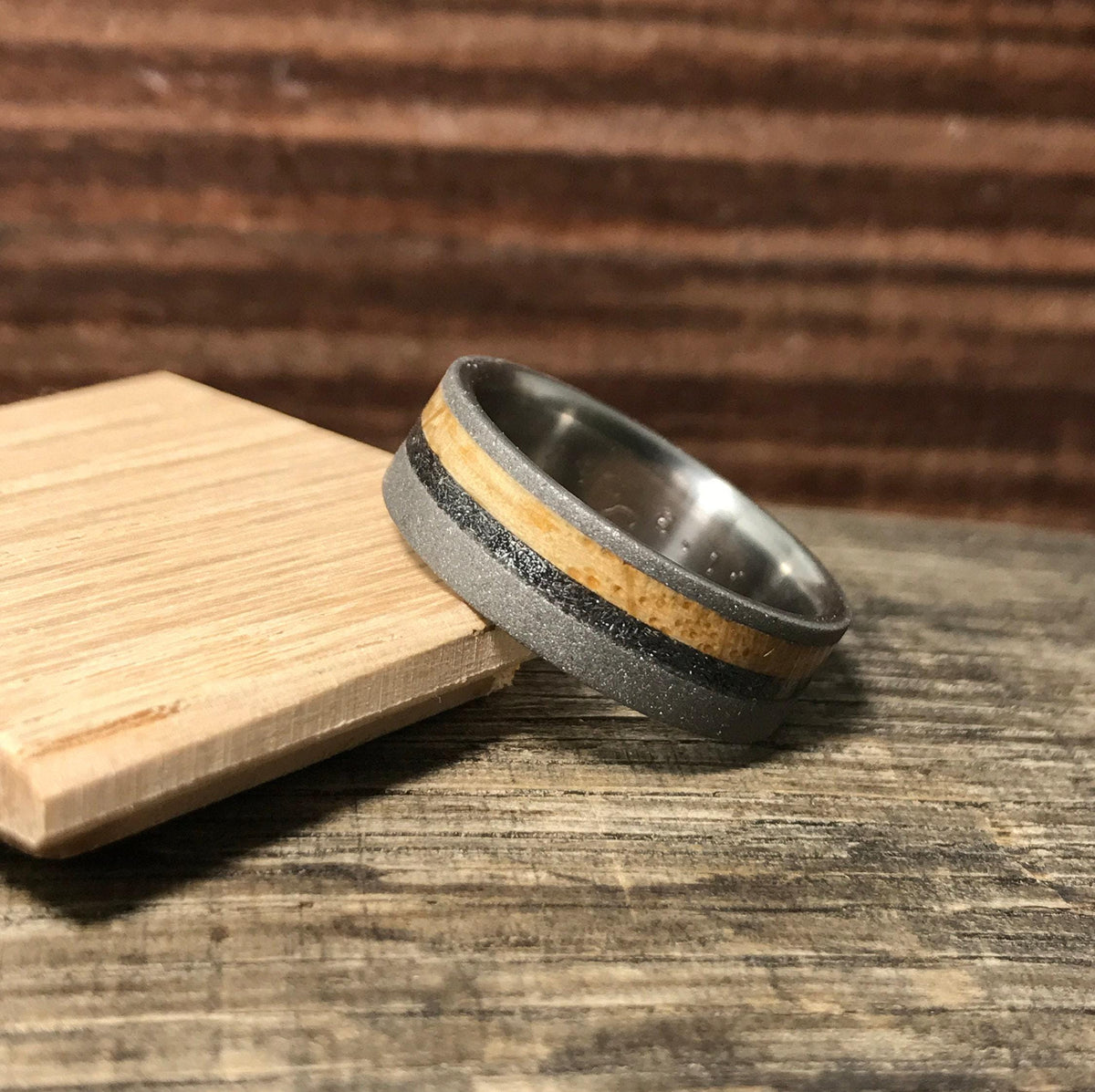 A close-up shot of the wedding band angled on a wooden block with a textured background.