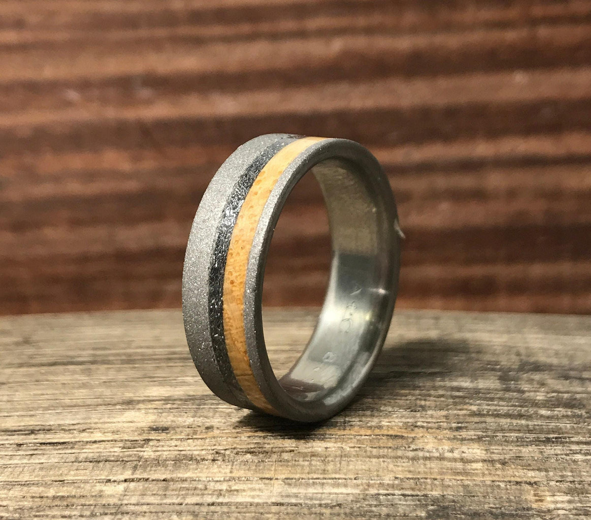 An angled view of the ring highlighting the textured sandblasted titanium edge next to the inlay details.