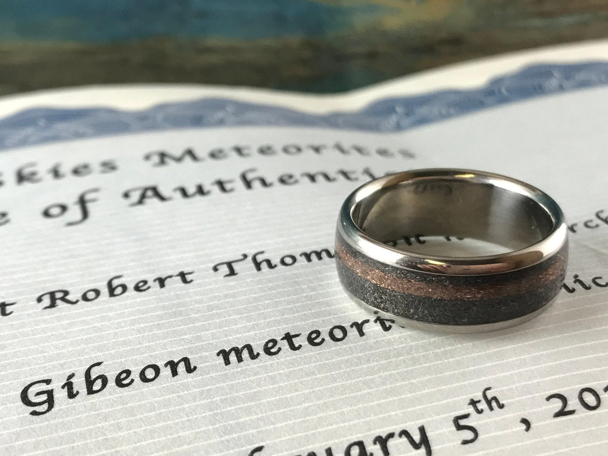 The titanium ring resting on top of a certificate of authenticity document detailing Gibeon meteorite.