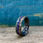 An angled view of the multi-material ring showing the swirling Damascus pattern and inlay details.