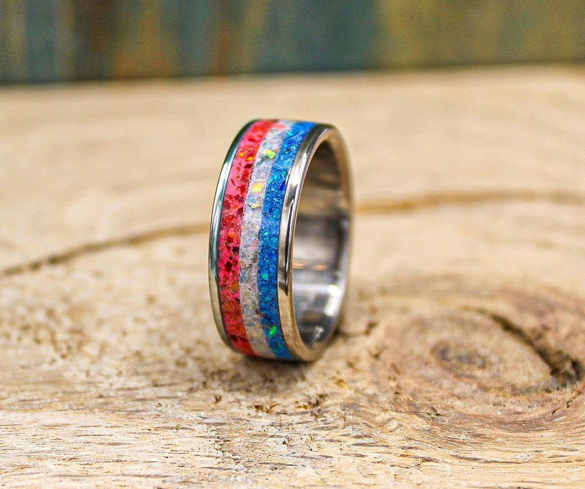 A final detailed view of the ring standing on the textured wooden tabletop, showing clear separation between the red, white, and blue opal sections.