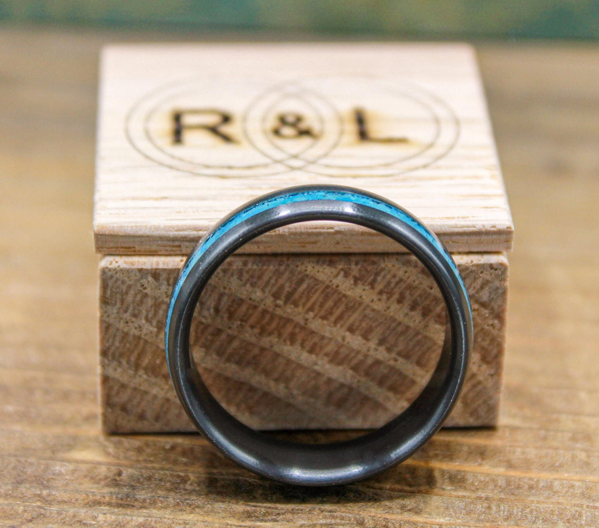 The ring is shown upright with its interior hollow visible in the foreground and a branded wooden box behind it.
