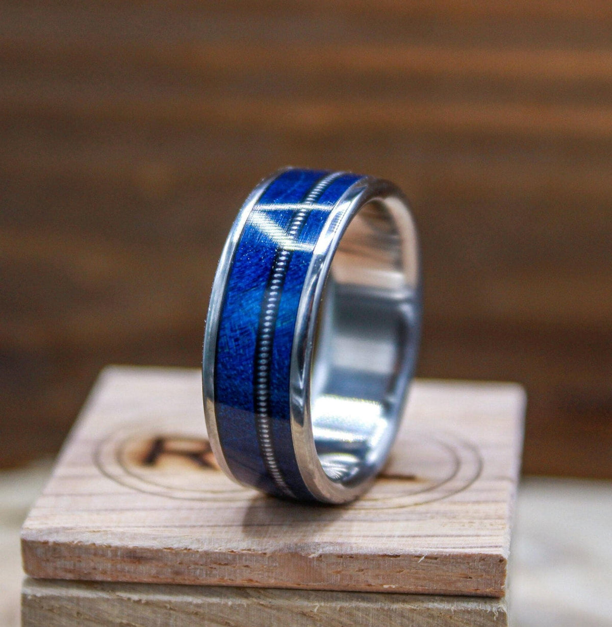 Titanium and blue wood ring for men with guitar string inlay.
