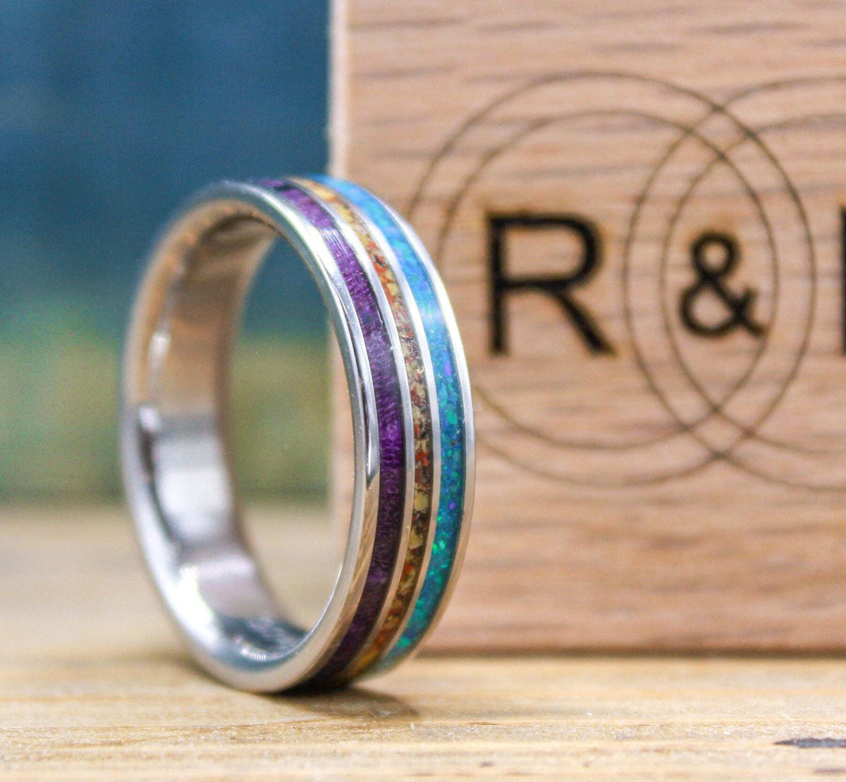 Made to order men's titanium wedding ring with dinosaur bone, opal and purple wood inlays.