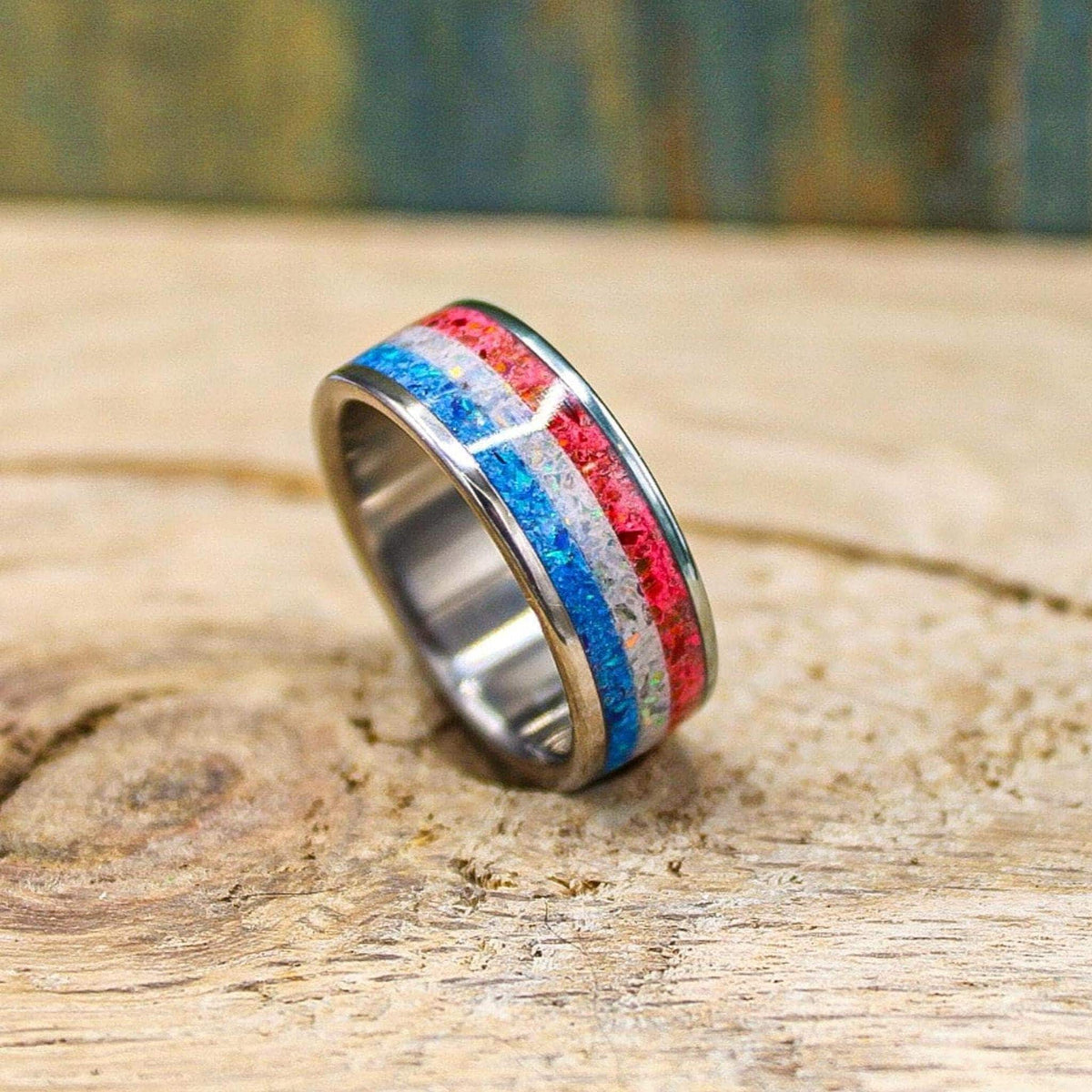 The ring presented upright from the opposite side, emphasizing the reflective metal interior and the textured red and blue exterior strips.