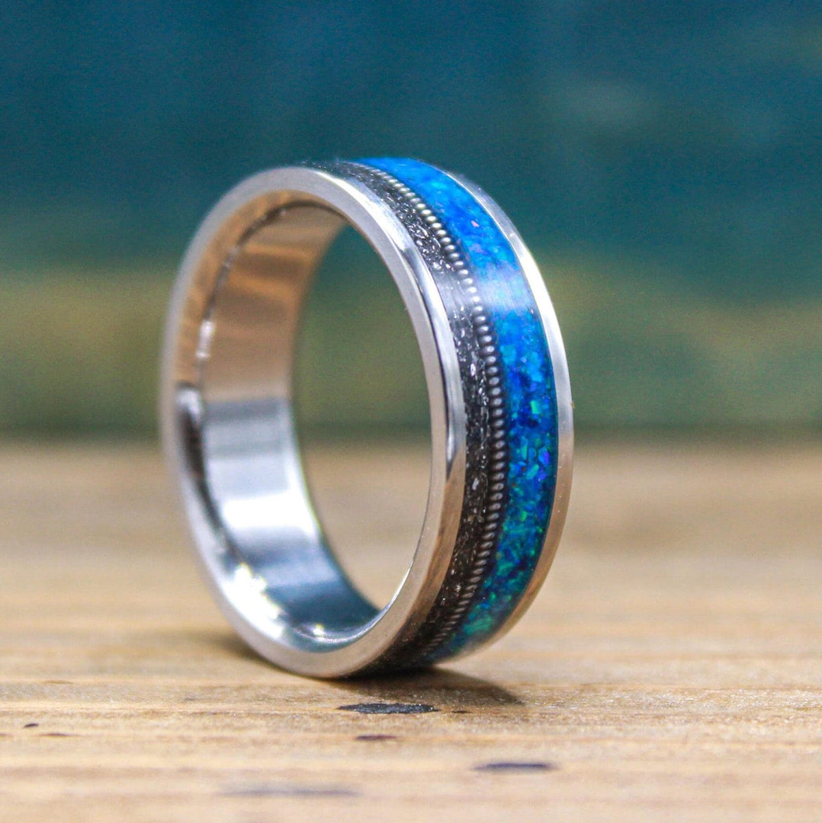 A close-up shot of the titanium band angled to display the detailed blue opal and meteorite inlays against a blurred background.