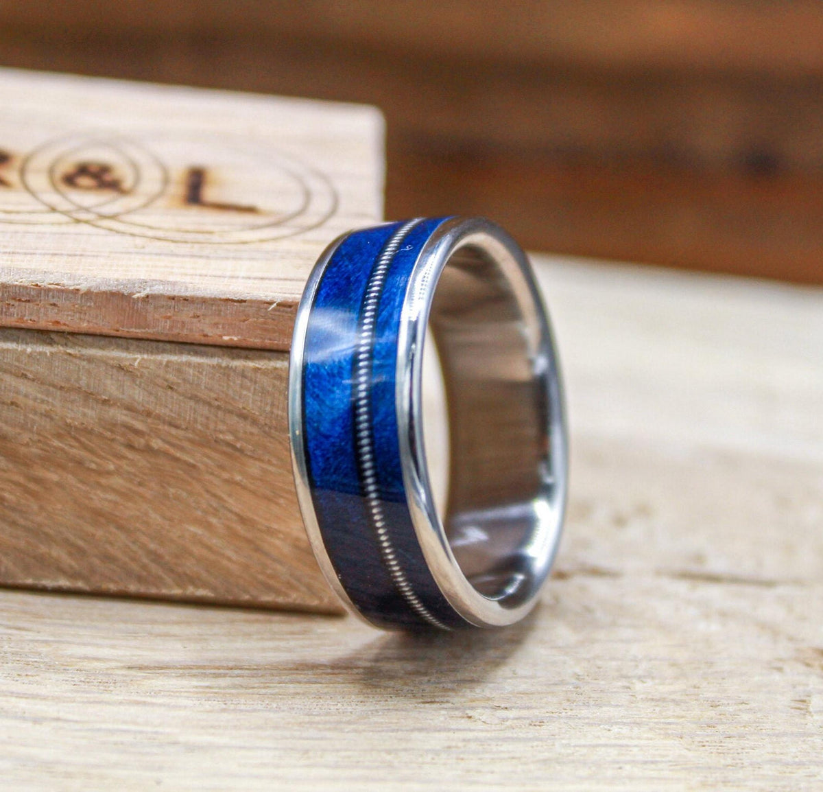 Titanium and blue wood ring for men with guitar string inlay.
