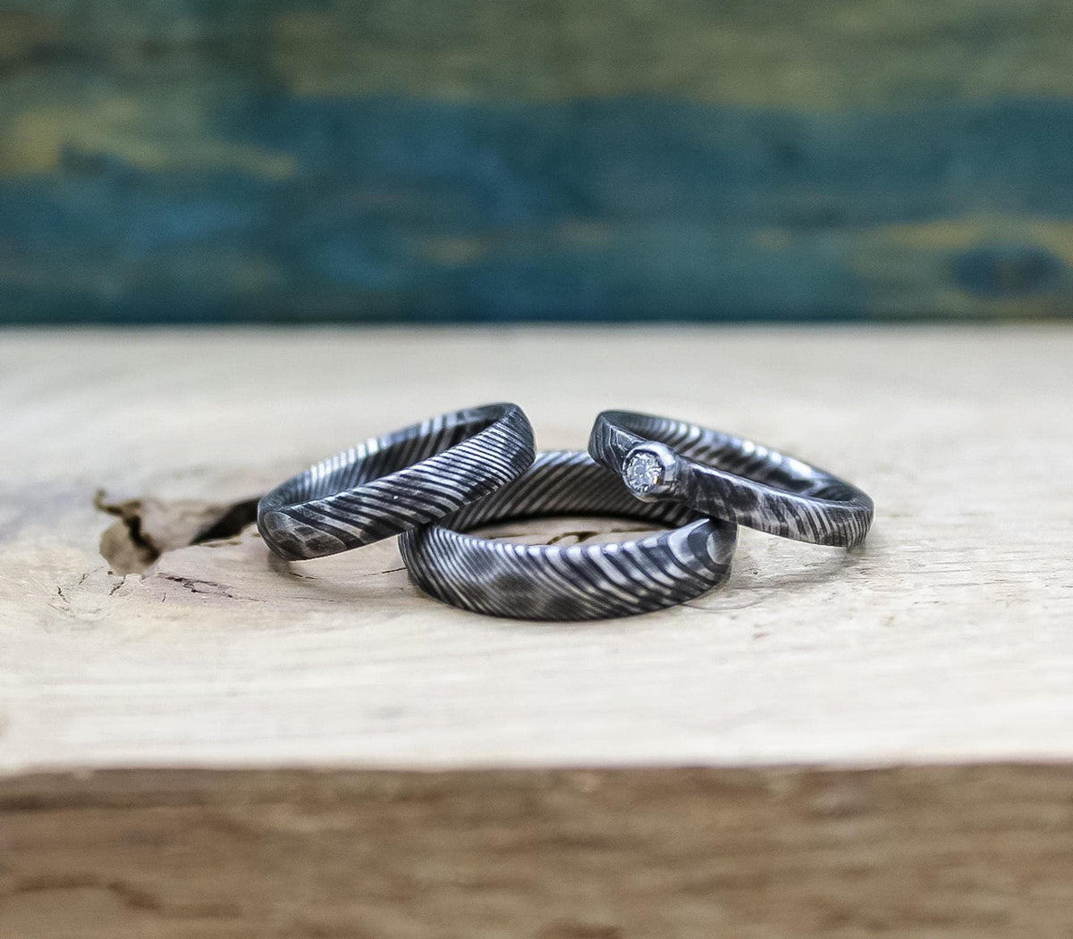 Damascus steel wedding set with his and hers bands and a diamond engagement ring, designed by RobandLean's rings.