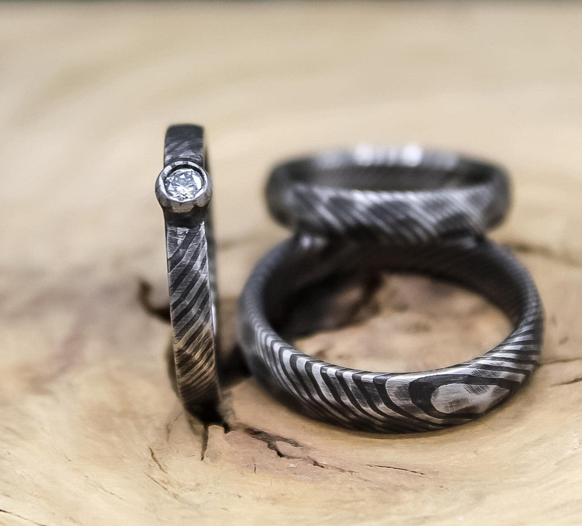 Damascus steel wedding set with his and hers bands and a diamond engagement ring, featuring RobandLean's rings craftsmanship.