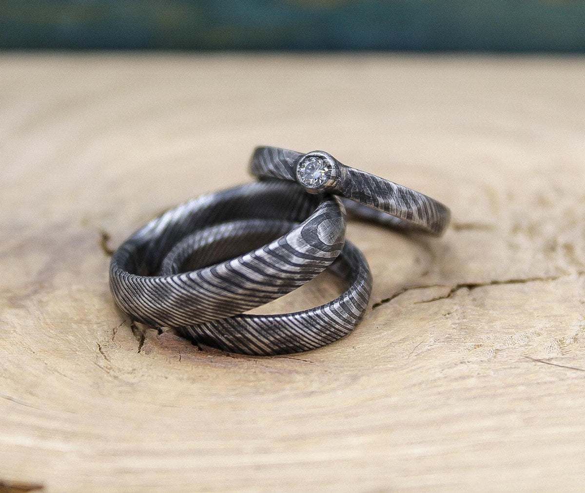 Damascus steel wedding set with his and hers bands and a diamond engagement ring, crafted by RobandLean's rings.