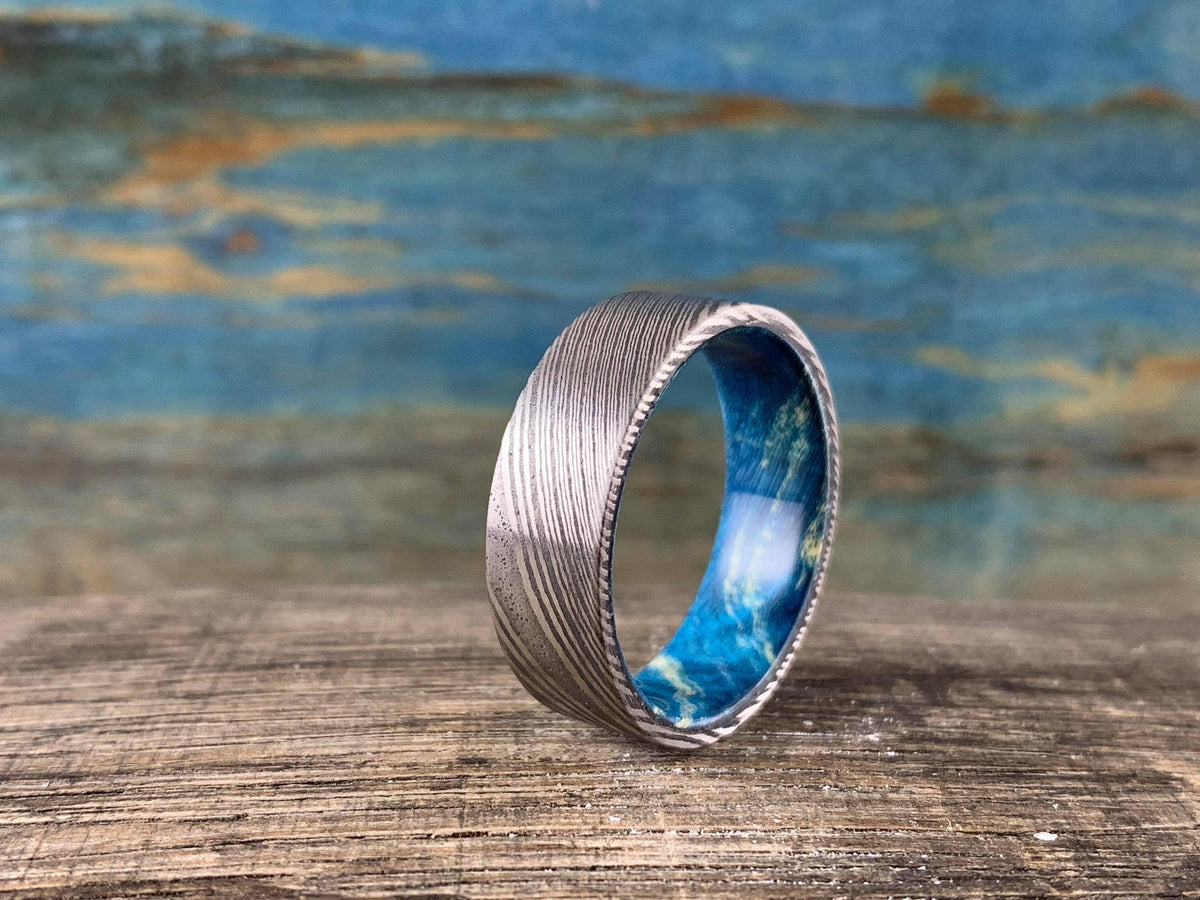 Damascus steel wedding band with blue box elder wood inlay, custom-made by RobandLean's rings, 4.5mm width, elegant and unique design.