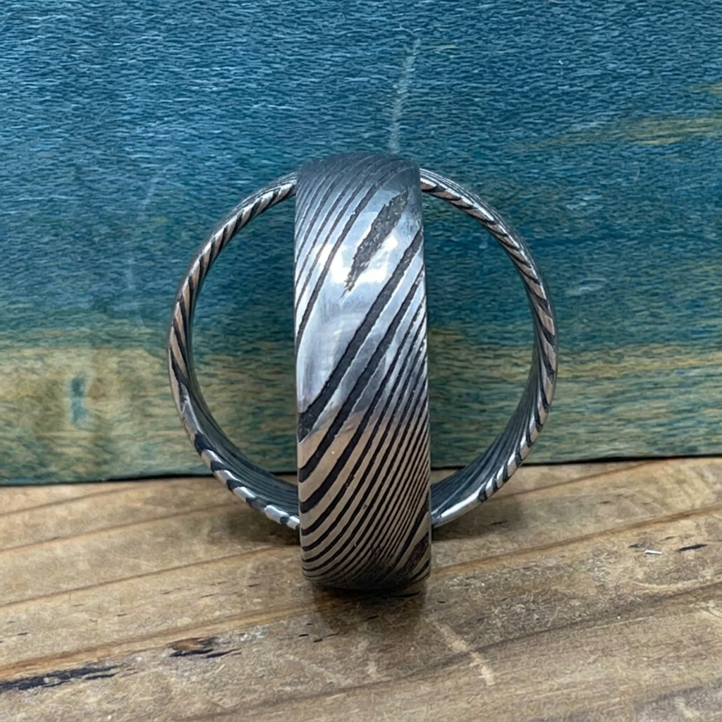 Damascus steel wedding band by RobandLean's rings with a square shape and intricate pattern on the surface.