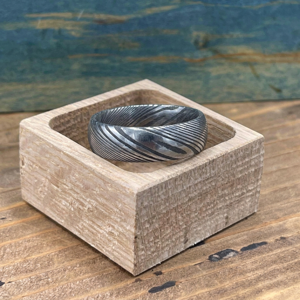 Damascus steel wedding band by RobandLean's rings, square-shaped with intricate pattern, showcasing craftsmanship and polished finish.