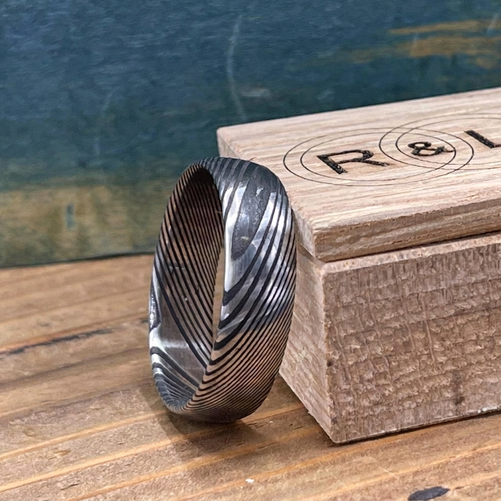 Damascus Steel wedding band by RobandLean's Rings with a square-shaped, intricate pattern on a polished surface.