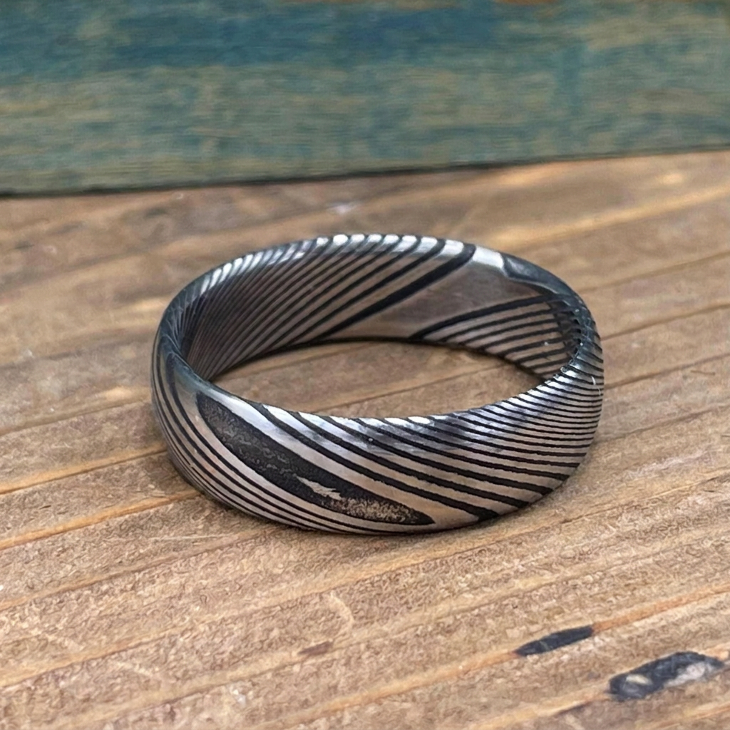 Damascus Steel wedding band by RobandLean's rings with a square-shaped, textured design on a silver band.