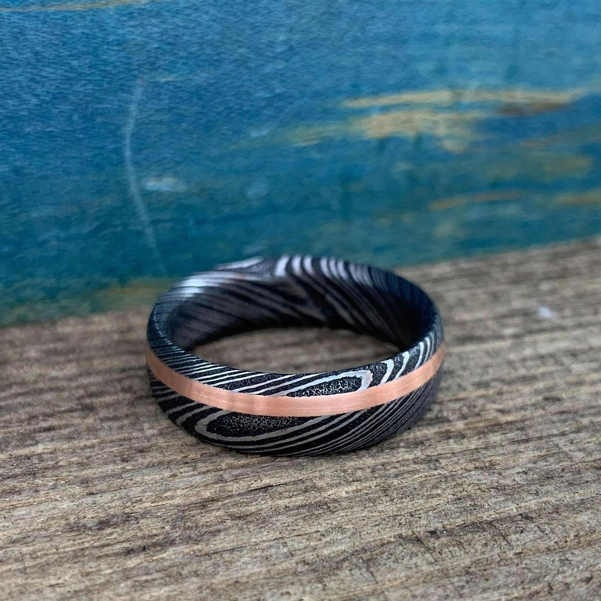 Damascus steel and copper men's wedding band with inlay, crafted by RobandLean's rings in stainless steel.