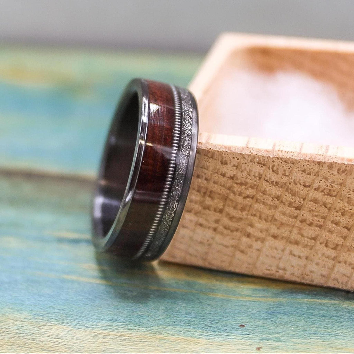 Black titanium men's wedding band with rosewood inlay, meteorite detail, and guitar string accents, by RobandLean's rings.