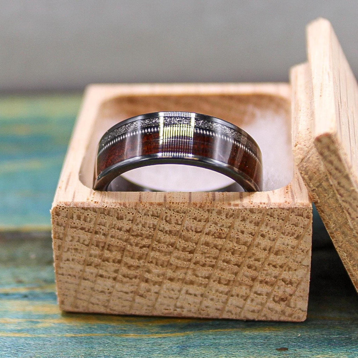 Black titanium men's wedding band with rosewood inlay, meteorite accents, and guitar string detail from RobandLean's rings.