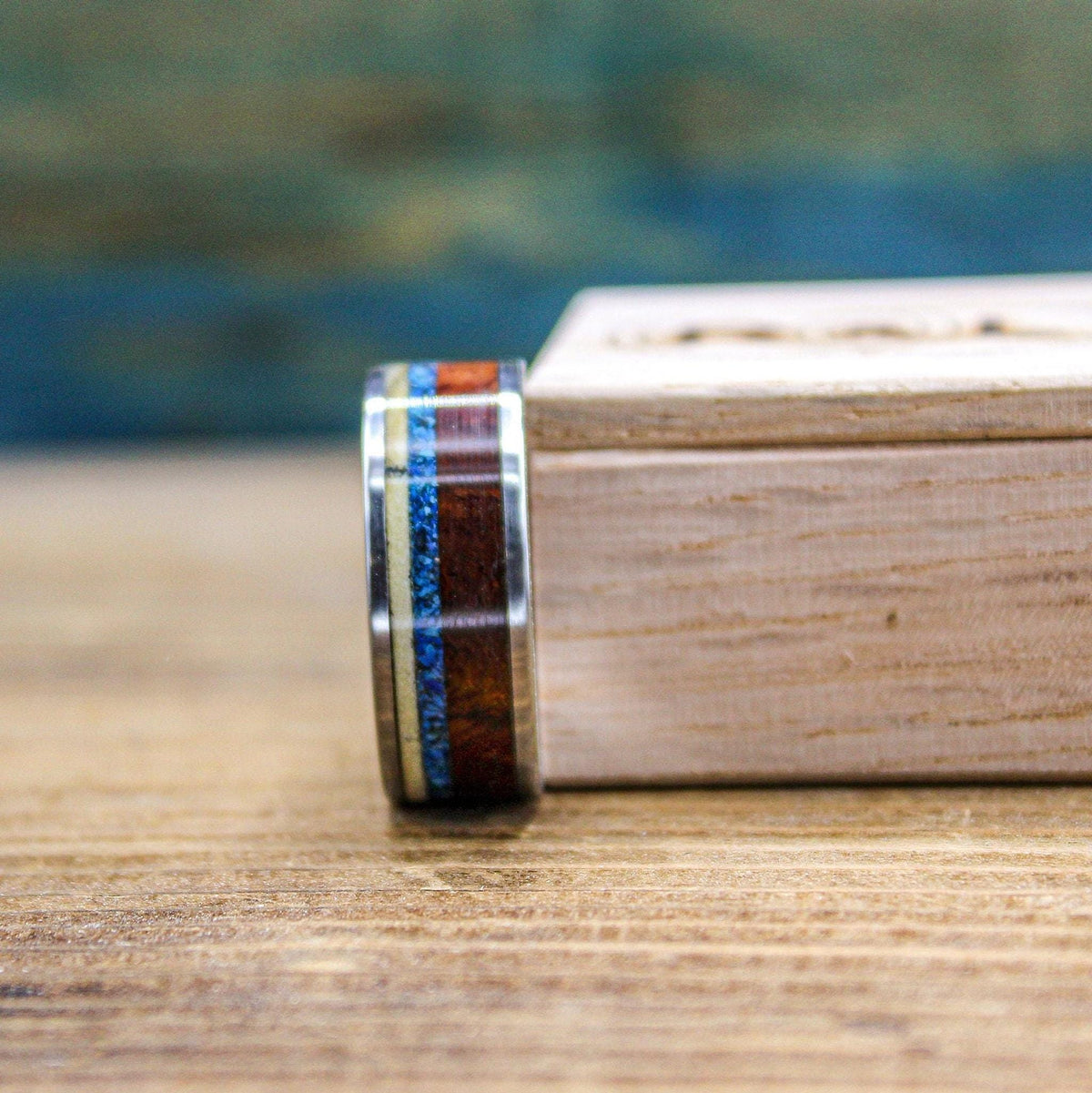 Titanium men's wedding band with Amboyna burl wood and turquoise inlay, showcasing a sleek design and natural wood accents.