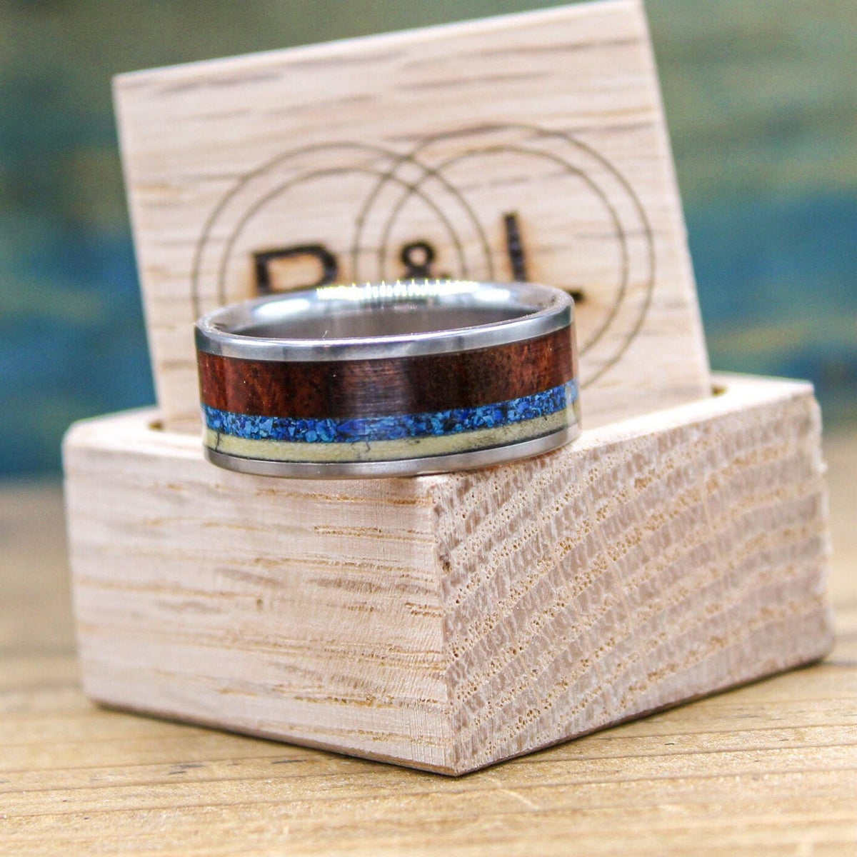 RobandLean's titanium men's wedding band with Amboyna burl wood and turquoise inlay, showcasing a sleek design and polished finish.