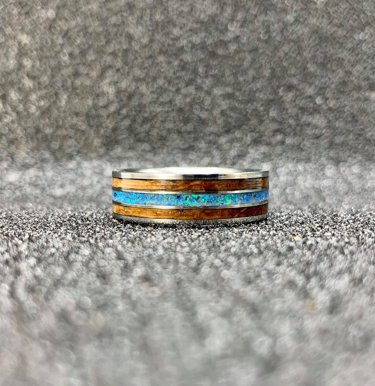 Titanium wedding band for him by RobandLean's with whiskey barrel wood, opal inlay, and engraved design.