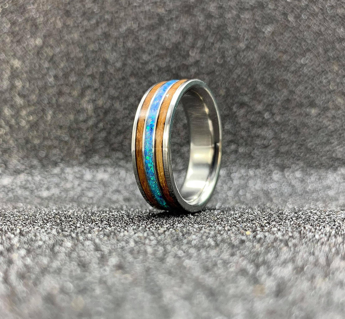 Titanium wedding band for him with whiskey barrel wood and opal, engraved design, featuring a 5.5mm width from RobandLean's rings.