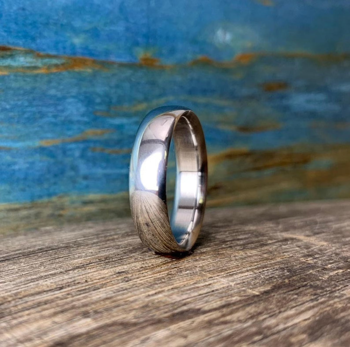 Close-up of smooth domed polished titanium wedding ring on wooden surface