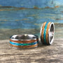 Titanium couples rings with charred whiskey barrel wood and glowing blue-green opal inlays
