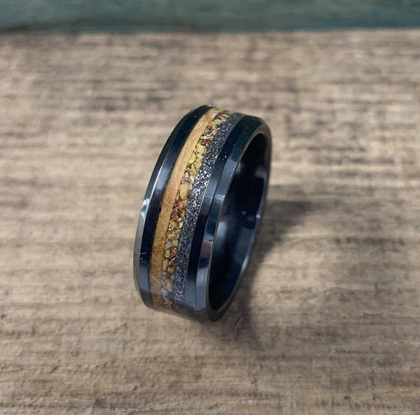 Men's black ceramic wedding band with meteorite, dinosaur bone, and whiskey barrel wood inlays