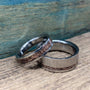 Matching his and hers titanium and recycled rose gold wedding bands on a wooden display