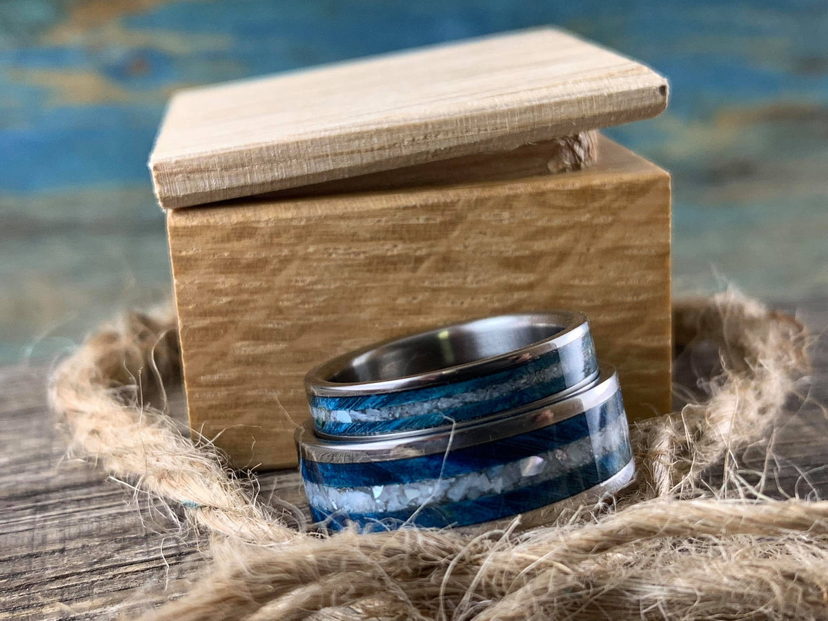 Custom titanium wedding bands with blue wood and pearl inlays, matching his and hers rings by RobandLean's rings.