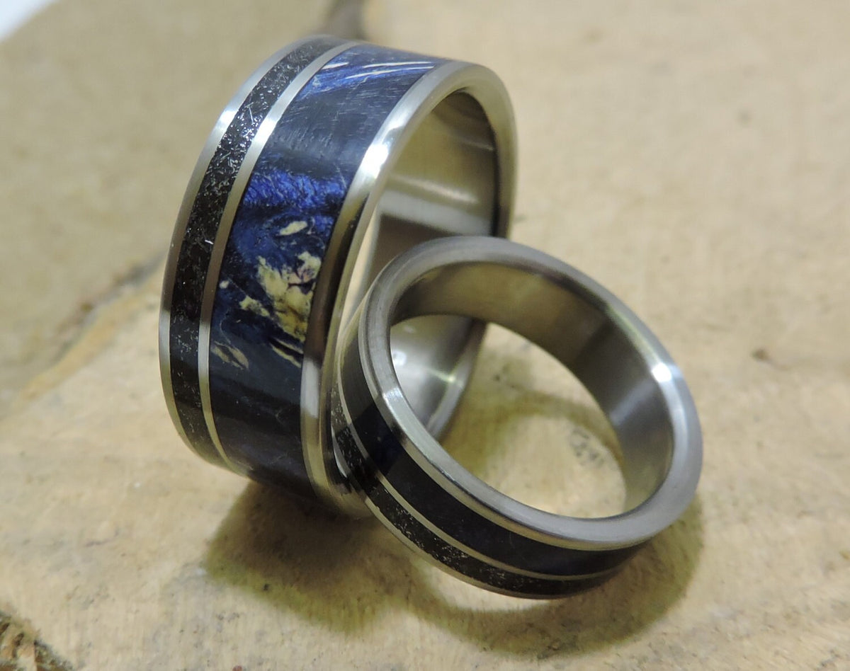 His and hers titanium wedding bands with meteorite and blue wood inlay, showcasing matching stylish and durable rings.