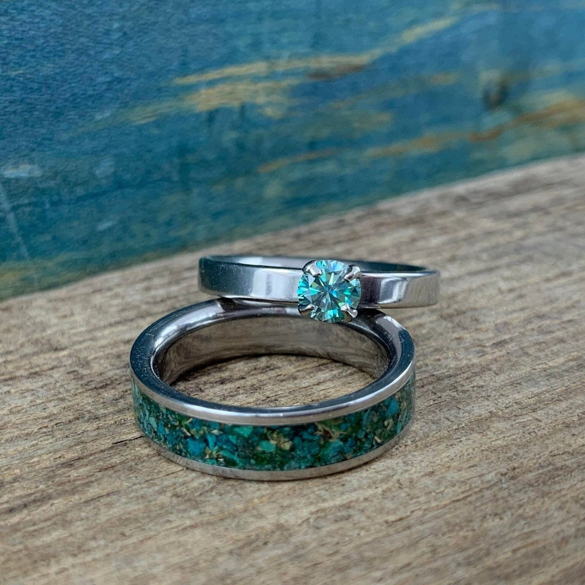 RobandLean's Hobgoblin set featuring two blue-green moissanite engagement rings with intricate band designs and sparkling stones.