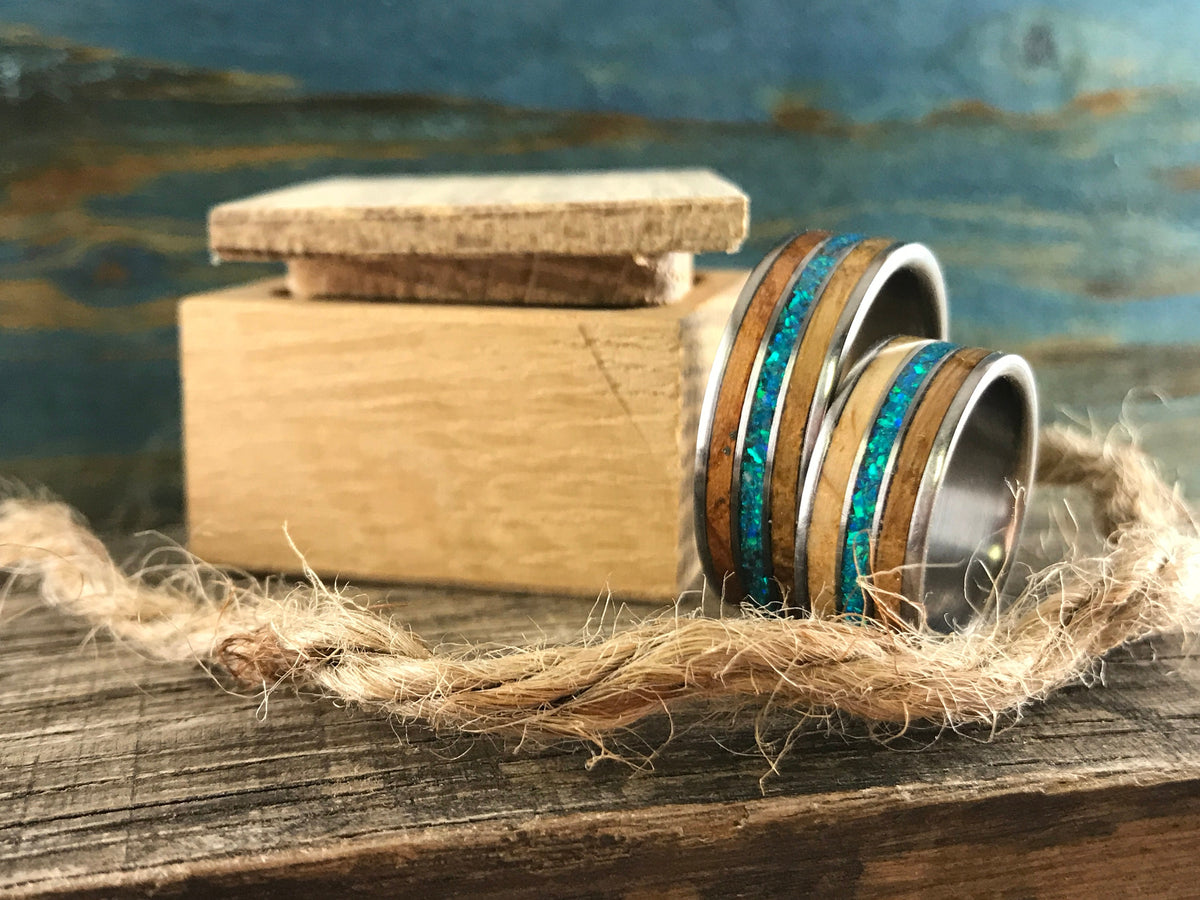 Titanium ring by RobandLean with whiskey barrel wood inlay and blue-green opal gemstone, showcasing craftsmanship and unique design.