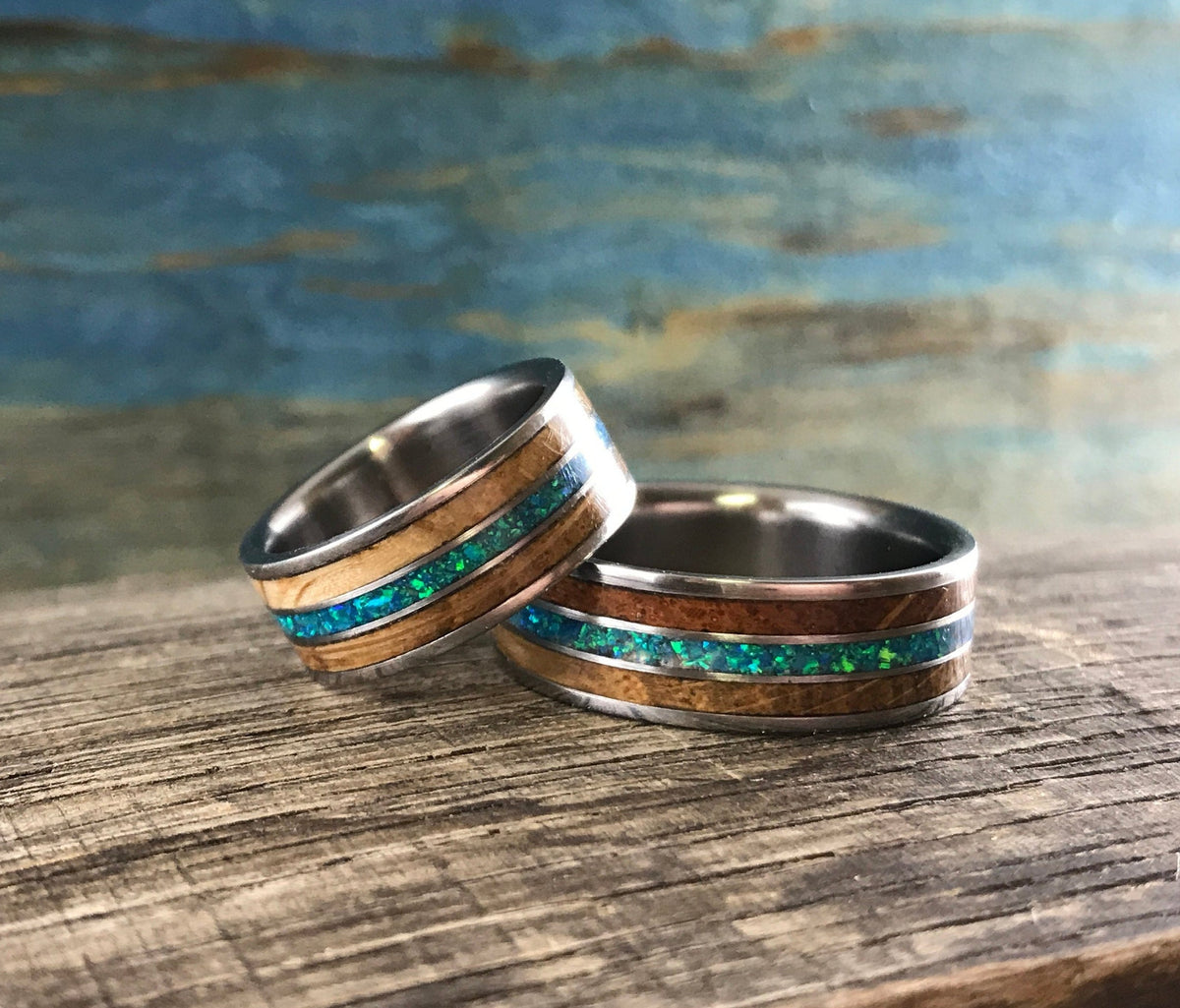 Titanium ring by RobandLean featuring whiskey barrel wood and blue-green opal inlaid design.