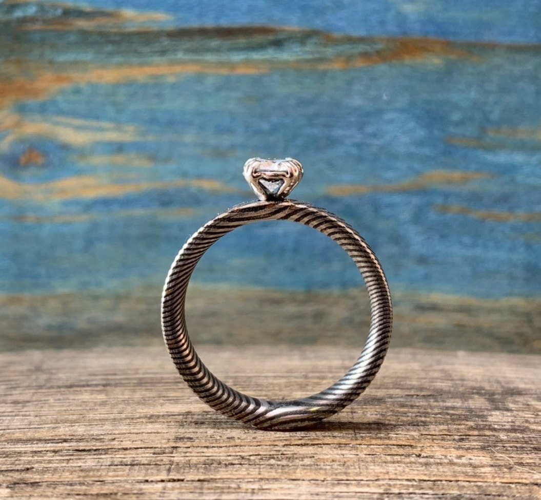 Ladies moissanite Damascus steel engagement ring with intricate pattern and sparkling stone from RobandLean's rings collection.