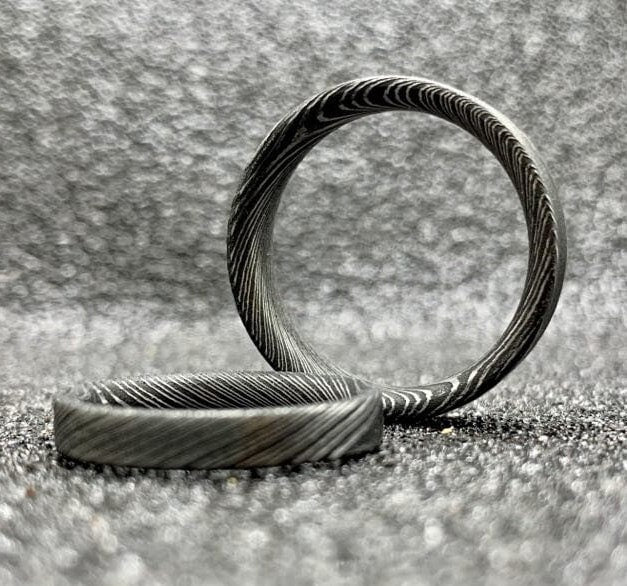 Custom handcrafted Damascus steel wedding band by RobandLean's Rings, featuring intricate pattern and polished finish.