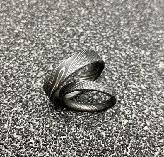 Custom handcrafted Damascus steel wedding band by RobandLean's rings, featuring intricate patterns and a polished finish.