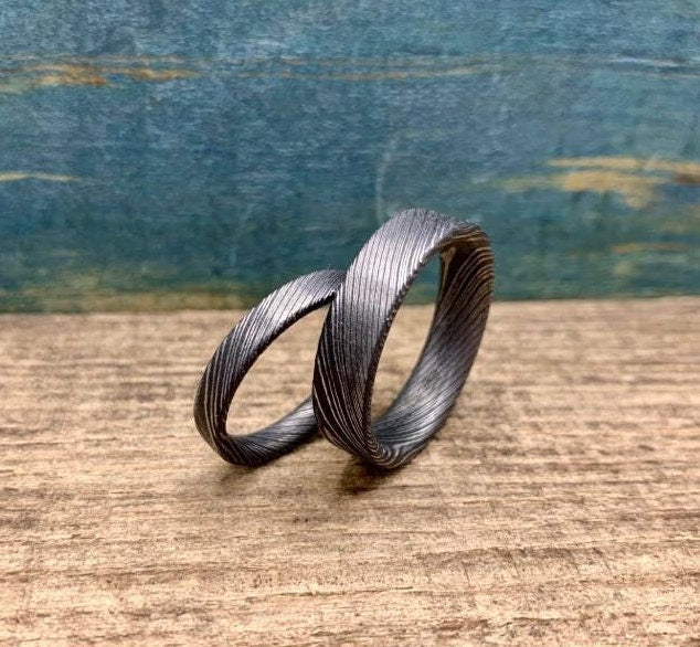 Custom handcrafted Damascus steel wedding band by RobandLean's rings, featuring intricate pattern and polished finish.