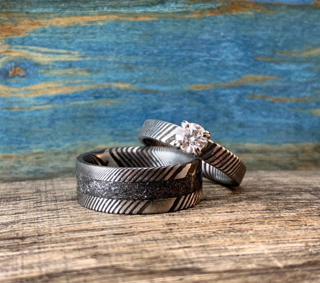 Damascus steel, meteorite, and moissanite matching wedding band set by RobandLean's rings, featuring intricate designs and sparkling gemstones.