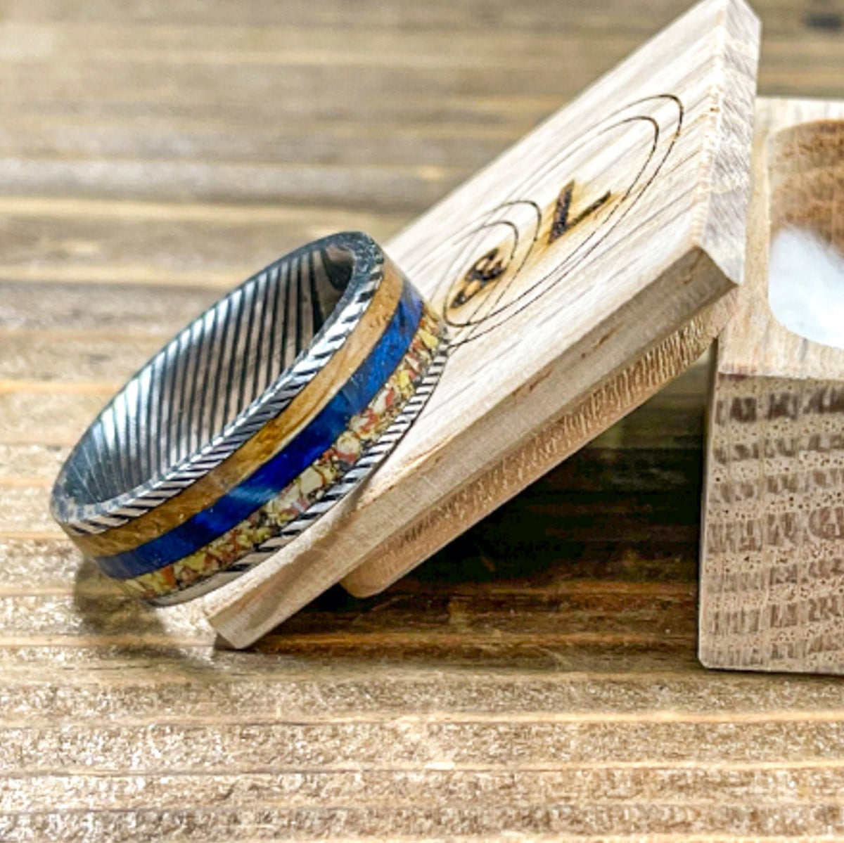 Damascus steel wedding band by RobandLean's rings featuring dino bone, blue box elder, and whiskey barrel wood inlay.